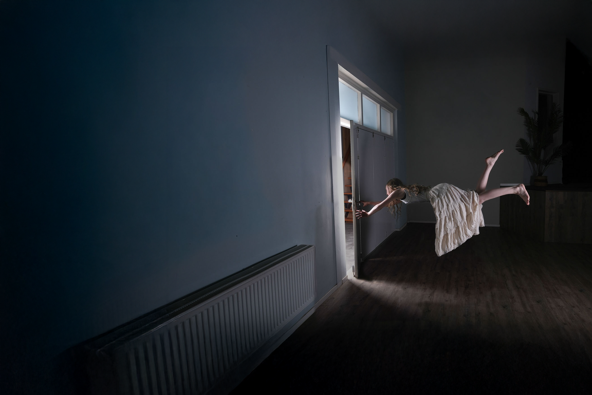 Een persoon zweeft naar een open deur in een donkere kamer