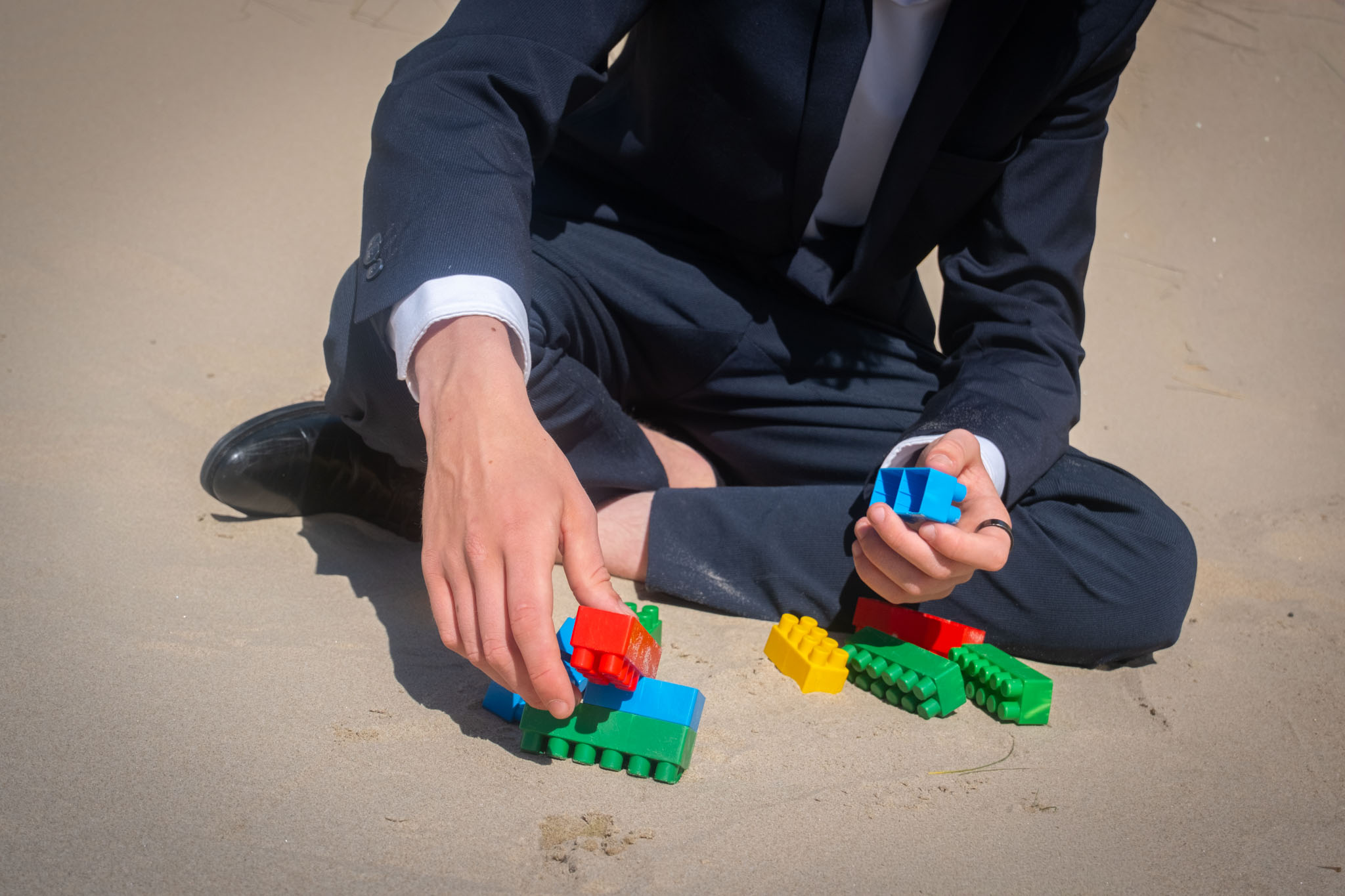 Handen plaatsen gekleurde bouwstenen in het zand