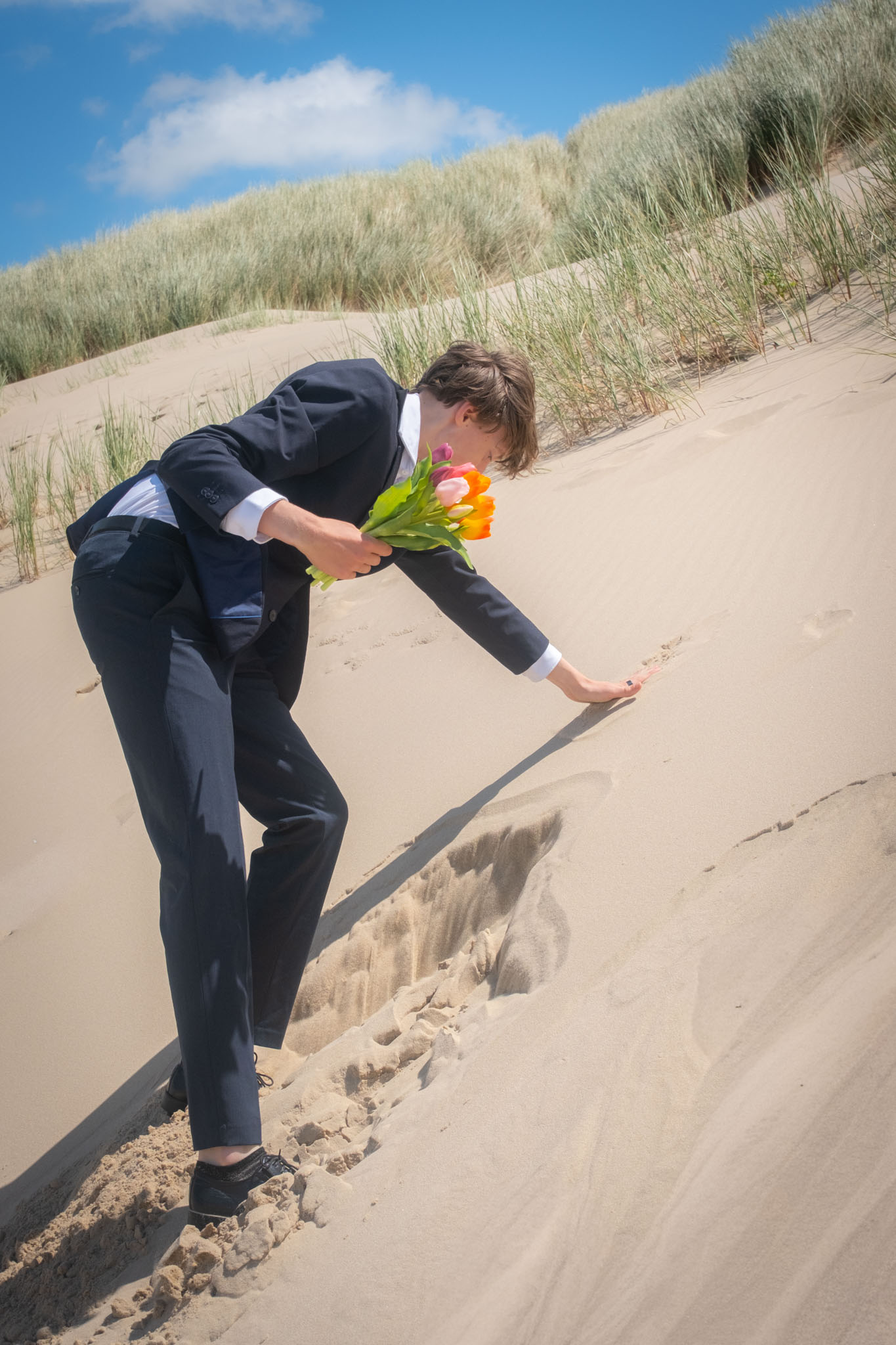 Een man in een pak rent met bouwstenen over een duin