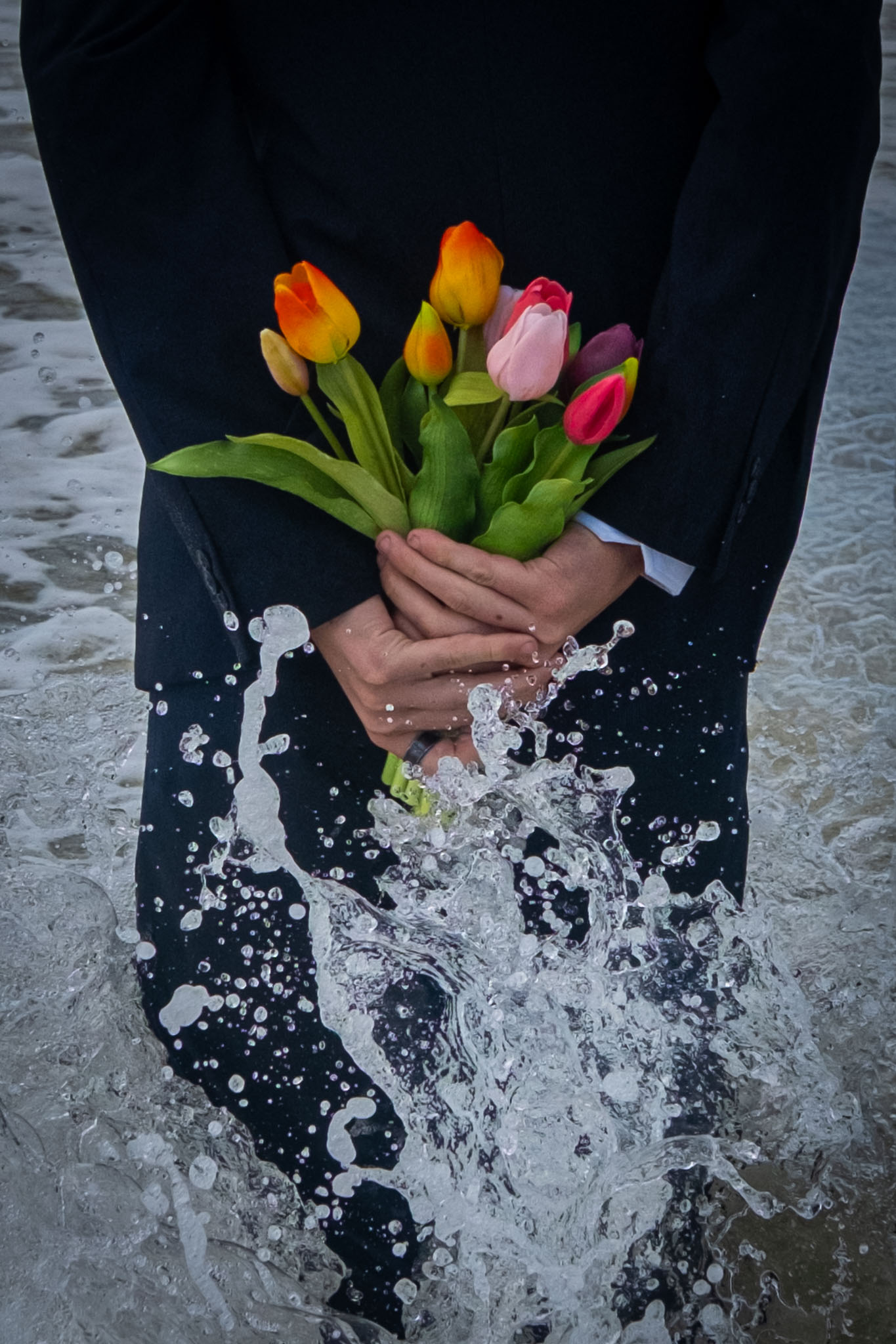 Handen houden tulpen vast terwijl een golf opspat