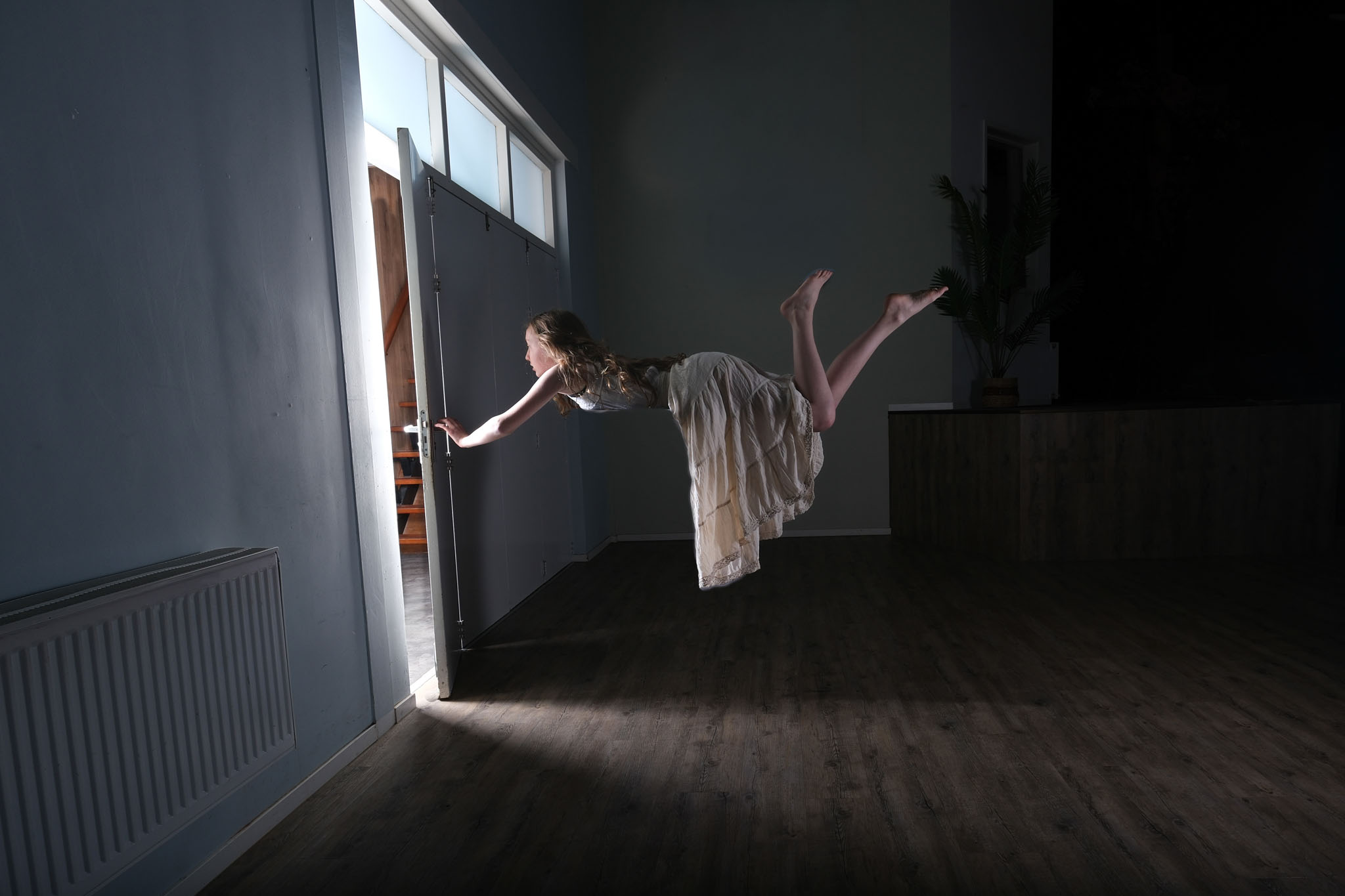 Een vrouw zweeft vlak voor de deuropening in een donkere kamer